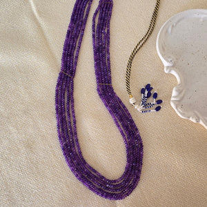 Purple beaded necklace on a beige fabric background