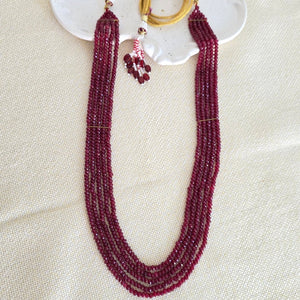 Beaded necklace with gold rings on a white shell against a beige background