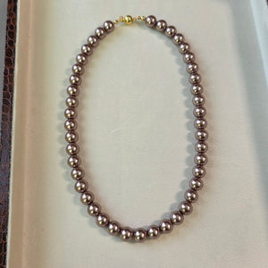 Magnetic metallic brown pearl necklace with gold magnetic clasp displayed in a jewelry box.