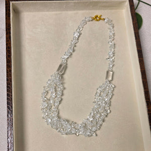 Silver necklace on a textured beige surface with a wooden frame