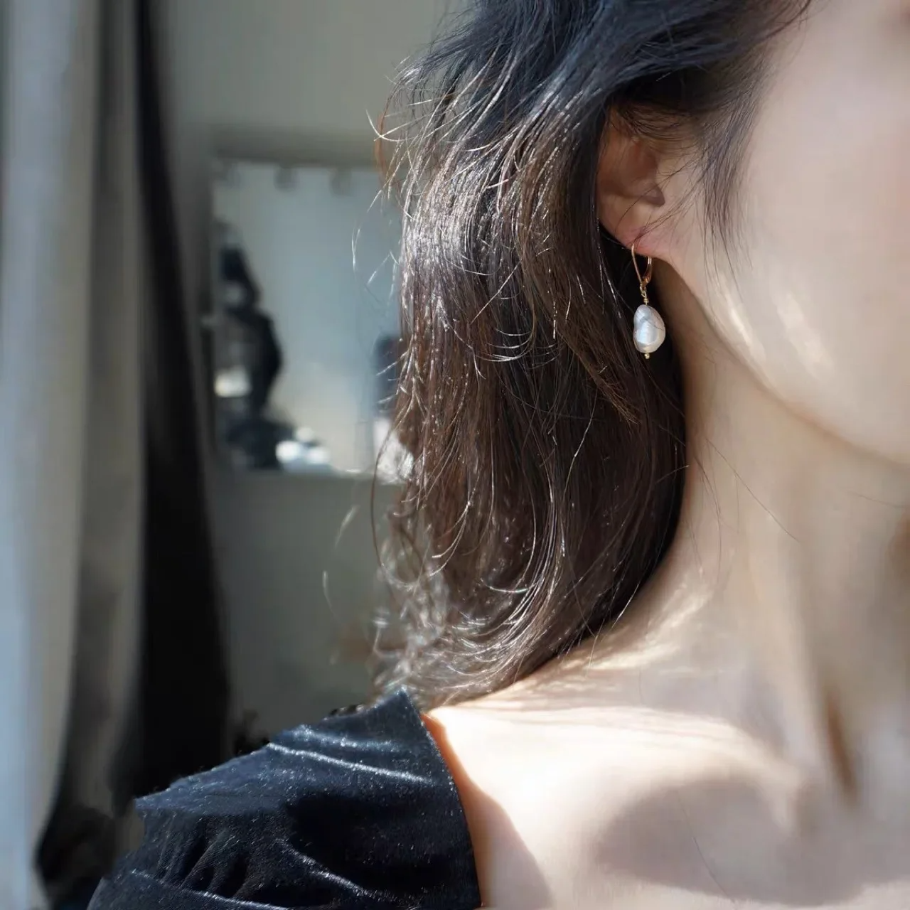 Elegant freshwater pearl drop earrings with gold lever-back hooks on white fabric background.