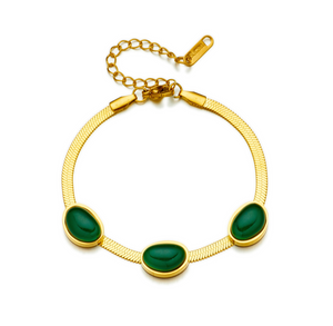 Gold bracelet with green stones on a white background