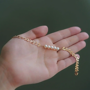 Elegant 18K gold-plated leaf bracelet with genuine freshwater pearls displayed on hand – minimalist nature-inspired jewelry for women