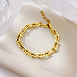 Gold chain bracelet on a white cushion