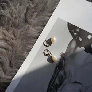 Elegant freshwater pearl drop earrings with gold lever-back hooks on white fabric background.