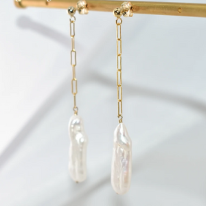 Gold chain earrings with pearl drops on a white background