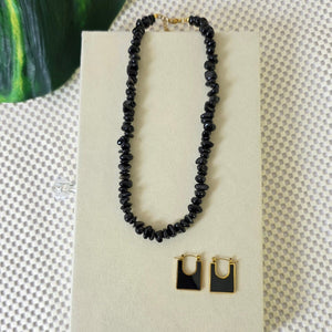 Black onyx gemstone necklace with matching gold-trimmed earrings on display.