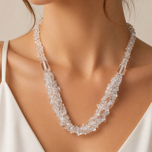 Close-up of a woman wearing a delicate beaded necklace against a neutral background