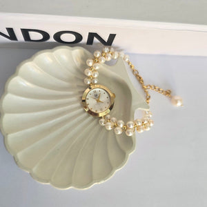 Pearl necklace on a shell-shaped stand with 'LONDON' branding in the background