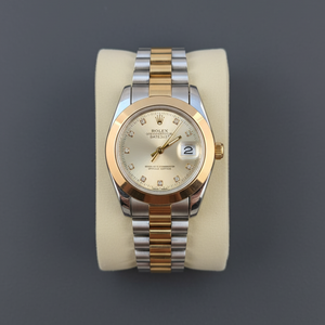 Luxury two-tone automatic wristwatch with diamond hour markers, gold and silver stainless steel bracelet, displayed on cushion