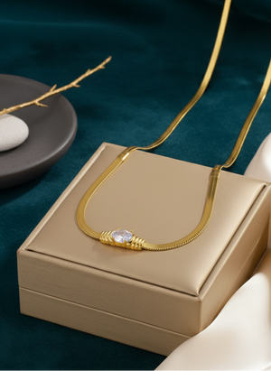 Gold necklace on a beige jewelry box with a dark green background