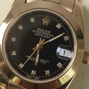 Gold Rolex watch with black dial and diamond accents on a light background