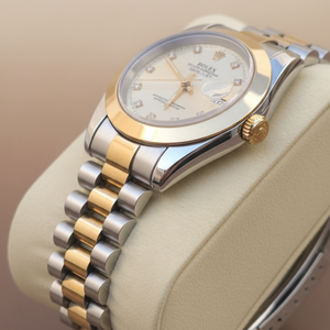 Luxury watch with two-tone metal bracelet on a beige background