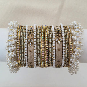 Collection of gold and silver bracelets on a white cylindrical stand against a beige background
