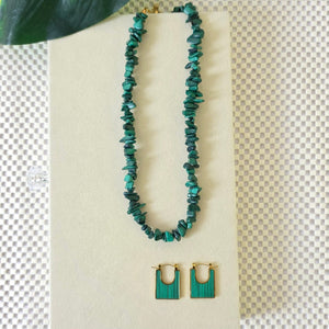 Green beaded bracelet on a beige card with a plant leaf in the corner