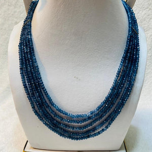 Blue beaded necklace on a mannequin bust against a light background