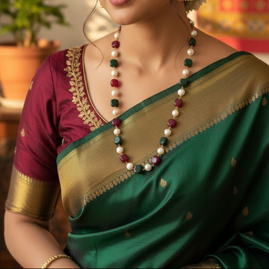 Woman in traditional green and maroon saree with jewelry in a decorated room
