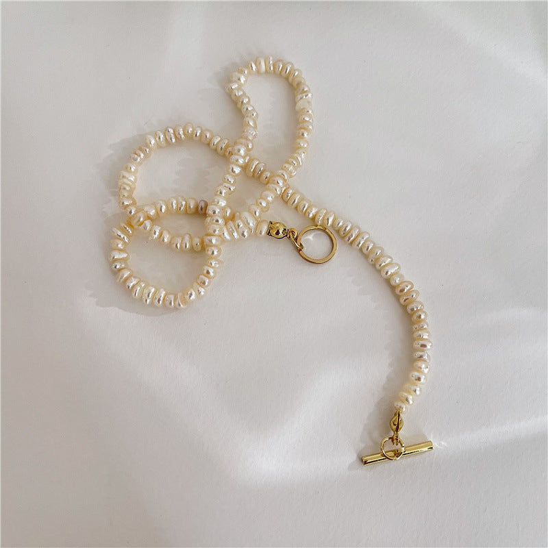 Close-up of a freshwater pearl necklace with gold toggle clasp on a soft background.