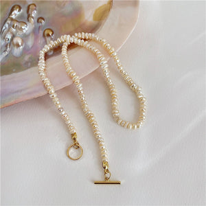 Close-up of a freshwater pearl necklace with gold toggle clasp on a soft background.