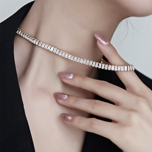 Close-up of a person wearing a sparkling gold bracelet on a plain background