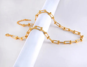 Gold chain necklace on a white fabric background