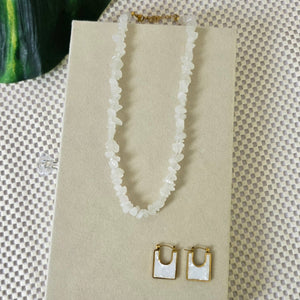 Necklace and earrings set on a beige card with a textured background