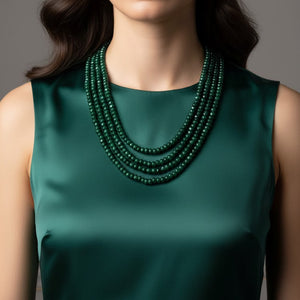 Green sleeveless top with a layered green jade necklace on a neutral background
