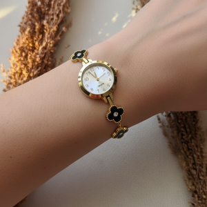 Gold watch with a floral design on a wrist against a neutral background