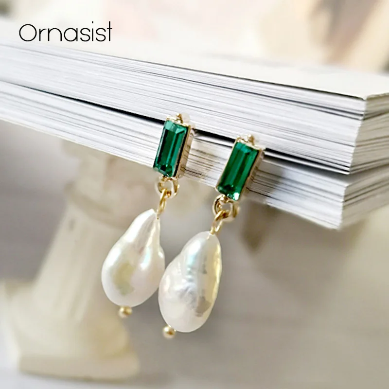 Pearl earrings with green gemstones on a stack of books, branded 'Ornasist'.