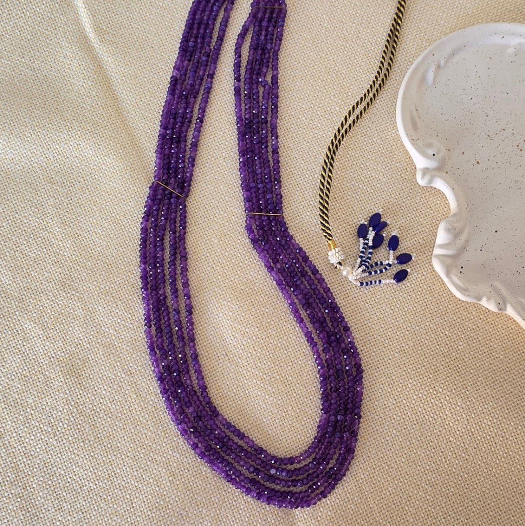 Purple beaded necklace on a beige fabric background