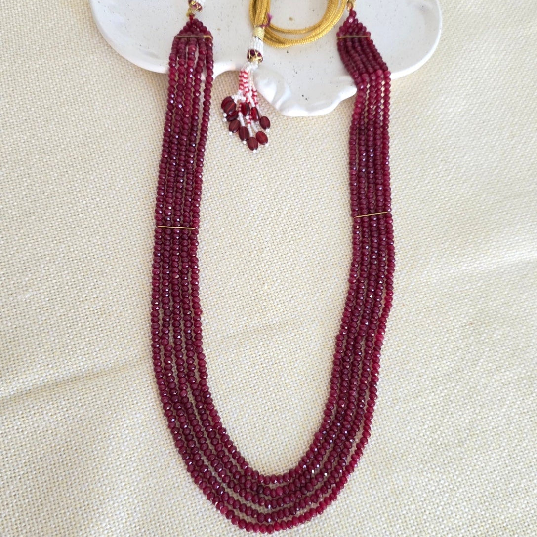 Beaded necklace with gold rings on a white shell against a beige background