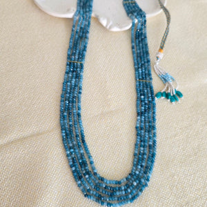 Blue beaded necklace on a beige surface