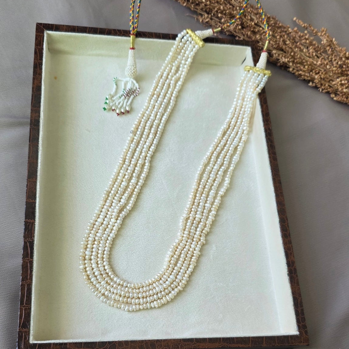 Handcrafted multi-strand freshwater pearl mala necklace with adjustable dori displayed in a jewelry box