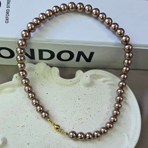 Magnetic metallic brown pearl necklace with gold magnetic clasp displayed in a jewelry box.