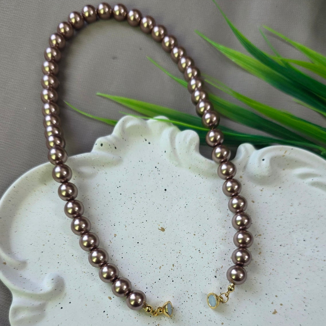 Magnetic metallic brown pearl necklace with gold magnetic clasp displayed in a jewelry box.