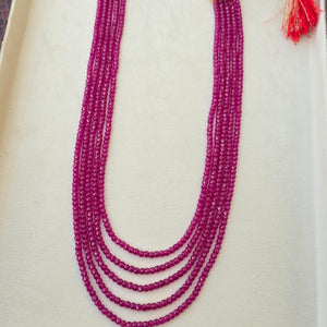 Purple beaded necklace with gold clasp in a wooden box on a white background
