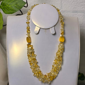 Yellow beaded necklace on a white stand with a soft focus background