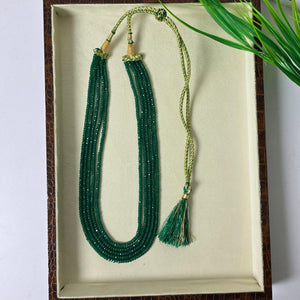 Green beaded necklace with tassels on a white surface