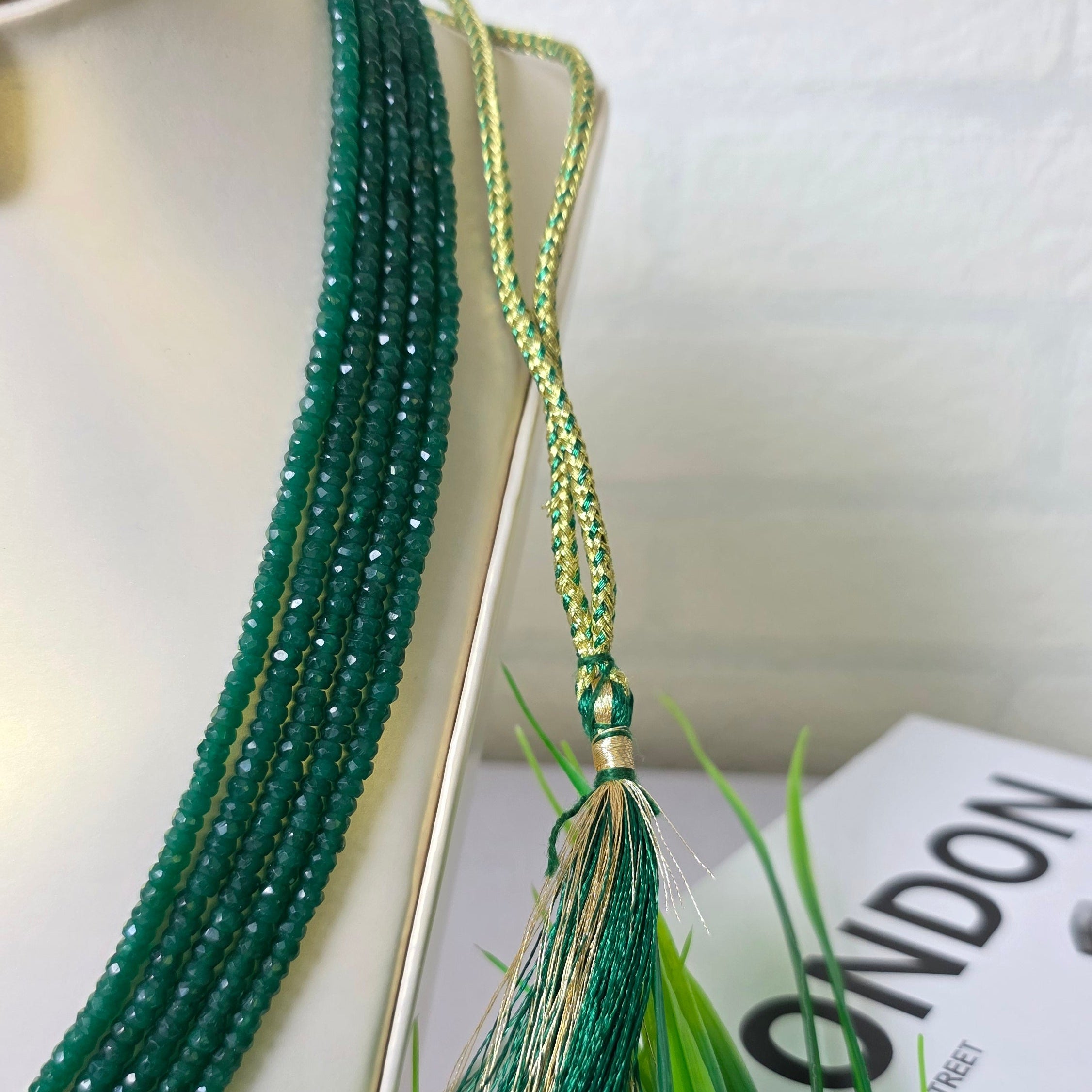 Green beaded bracelet with tassel on a white background