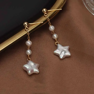 Gold-plated star-shaped freshwater pearl drop earrings by Urban Gear UG on brown fabric background

