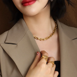 Woman wearing a gold chain necklace and rings, with a blurred background