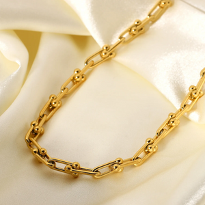 Gold chain bracelet on a soft white fabric background