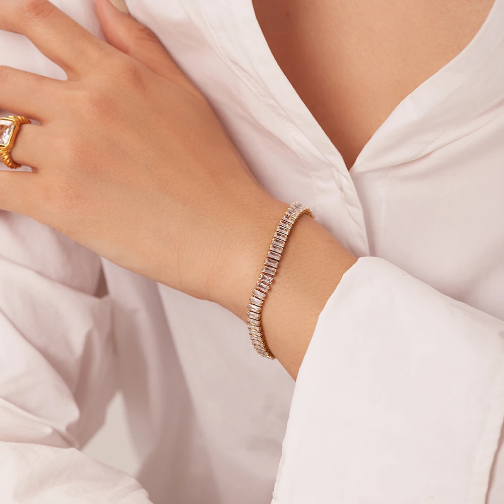 Close-up of a hand wearing a bracelet and ring on a light background