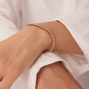Gold bracelet with clear stones on a wrist against a white background