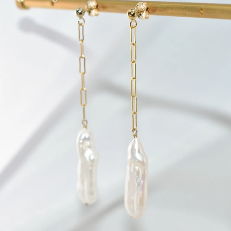 Gold chain earrings with pearl drops on a white background