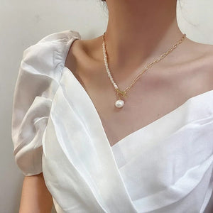 Model wearing an asymmetric freshwater pearl necklace, showcasing dual freshwater pearl beading and a gold chain, with a large pearl pendant adding a luxurious touch.