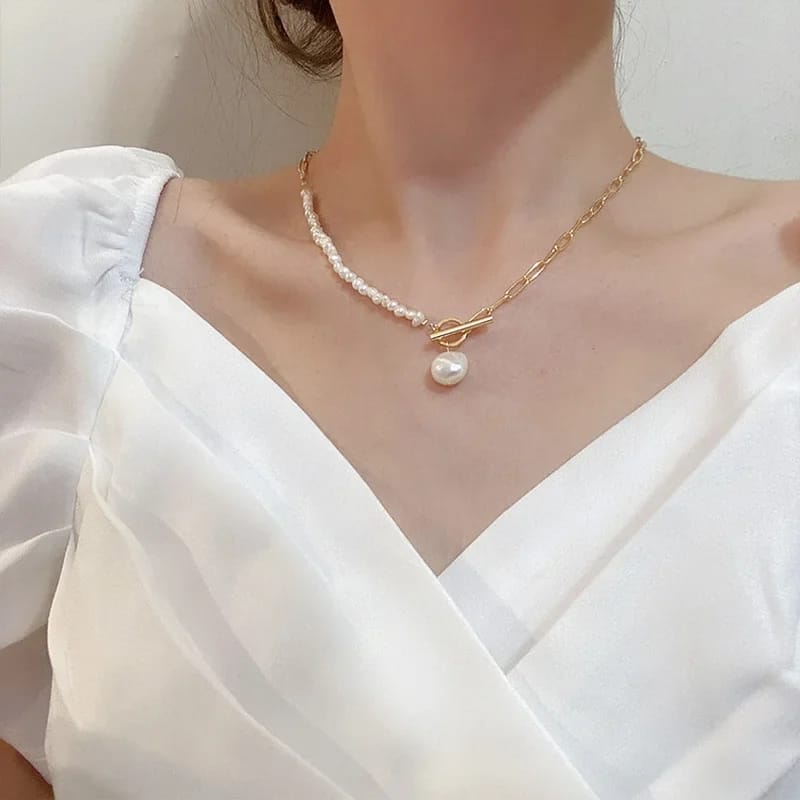 Model wearing an asymmetric freshwater pearl necklace, showcasing dual freshwater pearl beading and a gold chain, with a large pearl pendant adding a luxurious touch.