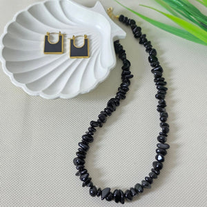 Black onyx gemstone necklace with matching gold-trimmed earrings on display.