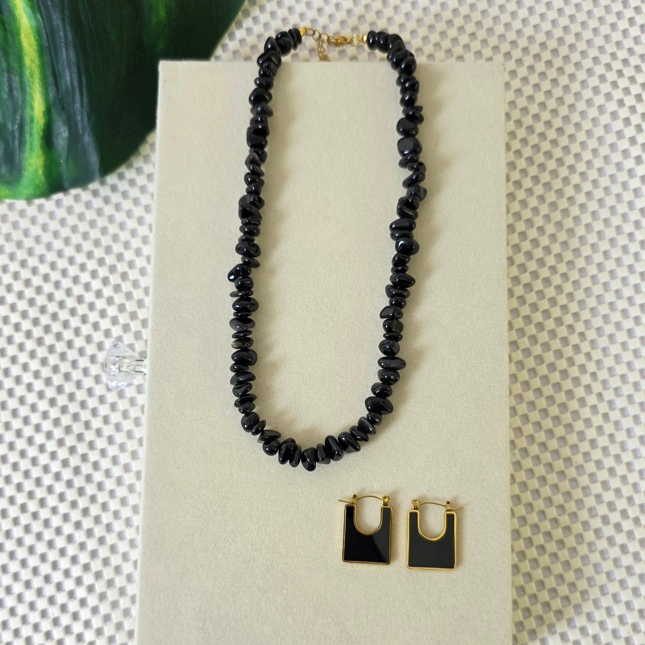 Black onyx gemstone necklace with matching gold-trimmed earrings on display.