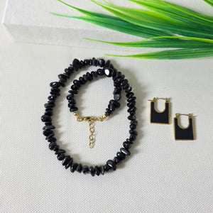 Black onyx gemstone necklace with matching gold-trimmed earrings on display.
